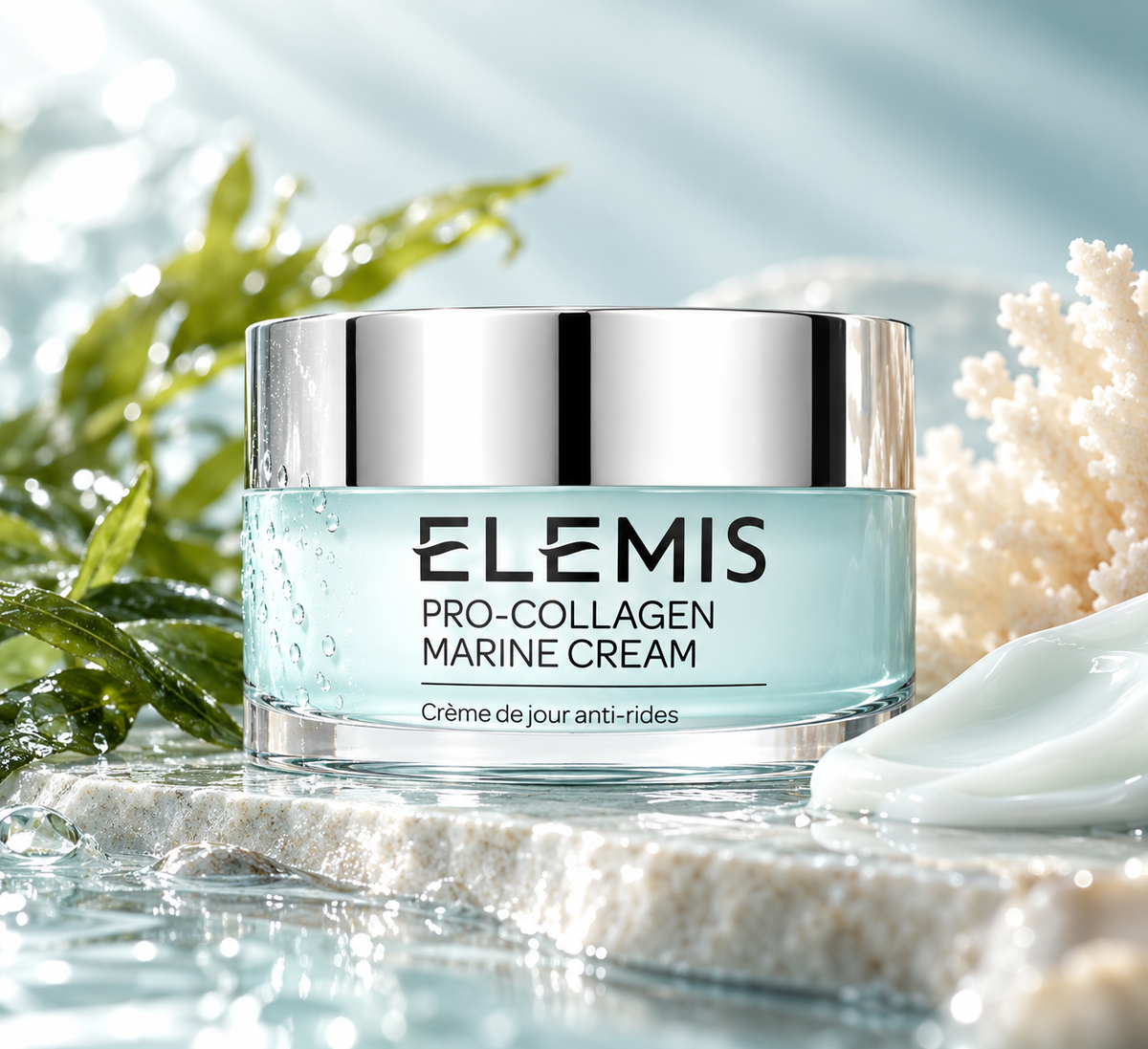 ELEMIS Pro-Collagen Marine Cream luxury anti-aging moisturizer in a pale blue jar with a silver lid, surrounded by fresh green leaves, white coral, water droplets and a silky cream texture. Hydrating, firming facial cream beautifully presented in a refreshing marine-inspired skincare setting.